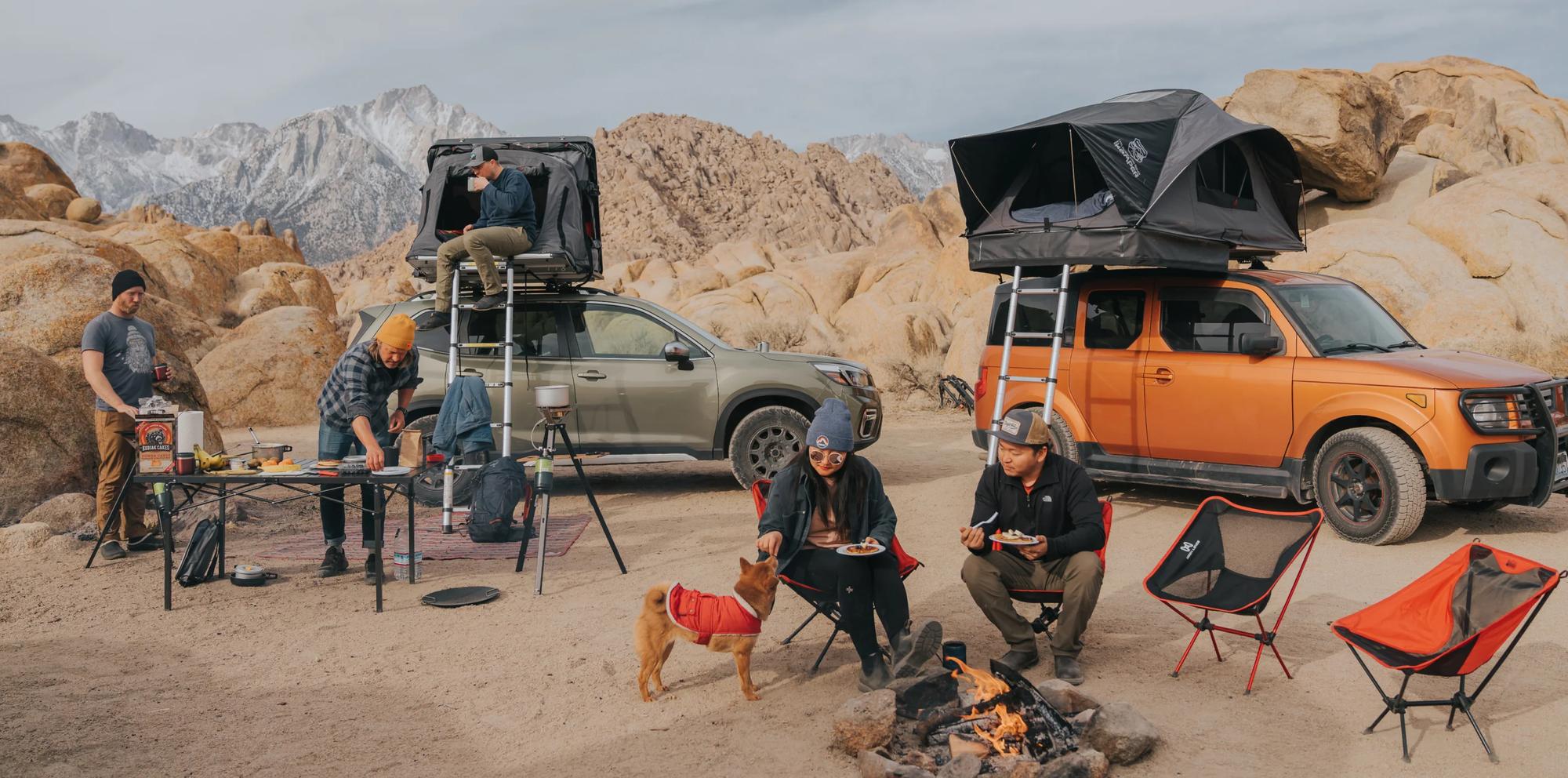 Aventureros acampando con tiendas de techo Overvian en terreno rocoso - dos SUVs con rooftop tents desplegadas al atardecer